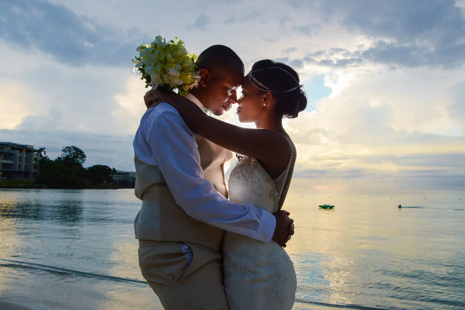 A bride and groom embrace forehead to forehead on a Caribbean beach at sunset
