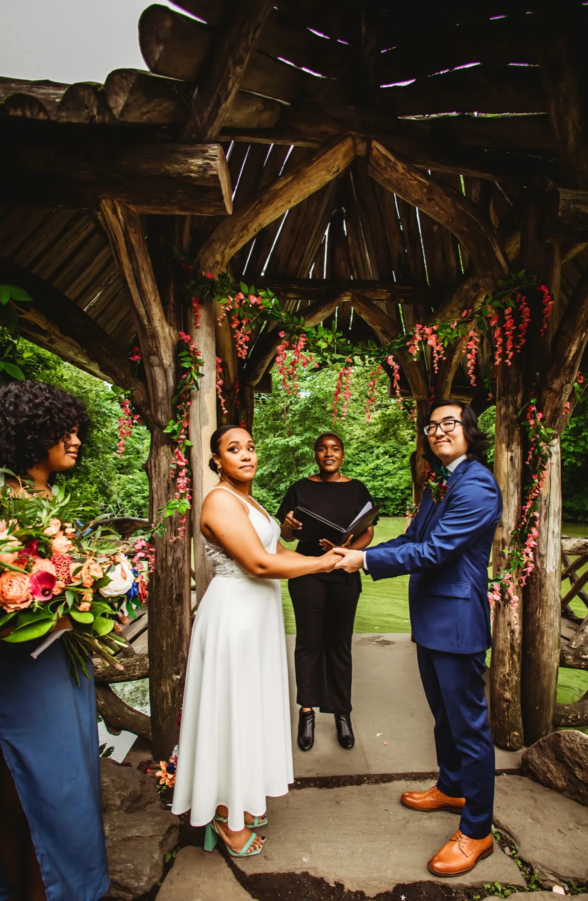 A couple holding hands during their vows at a Central Park arch