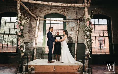 A couple exchanging vows in a simple ceremony arch setting