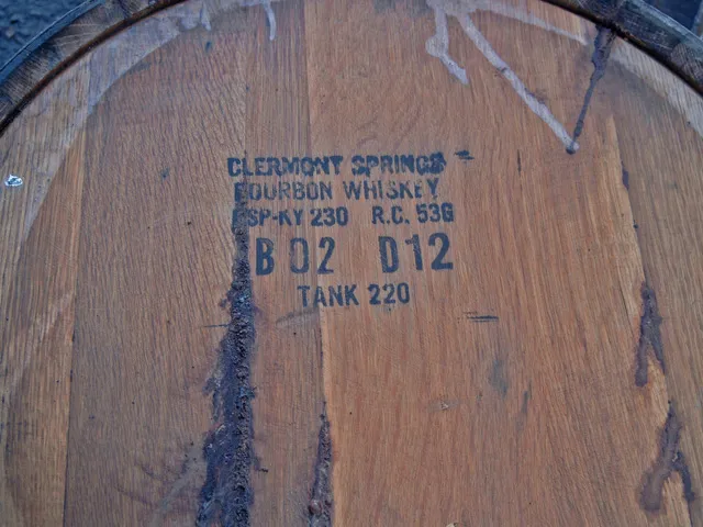 The head of a charred oak barrel stamped 'Clermont Springs Bourbon Whiskey,' with dark spirit streaks running down the grain