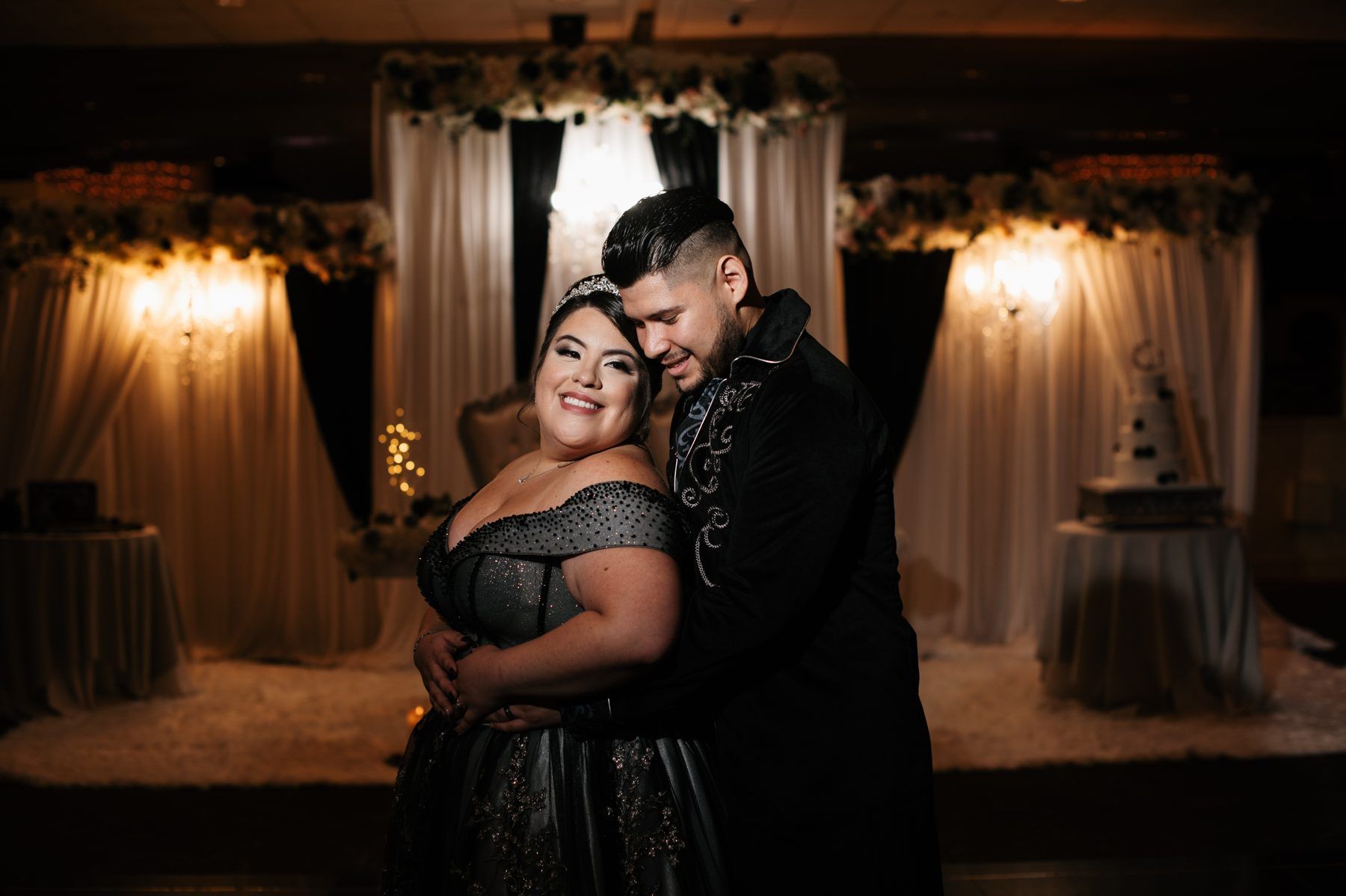 A couple embracing in a candlelit ballroom at their gothic Halloween wedding