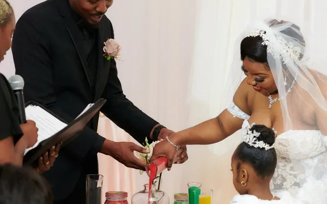 A couple pouring colored sand into a vase during their wedding