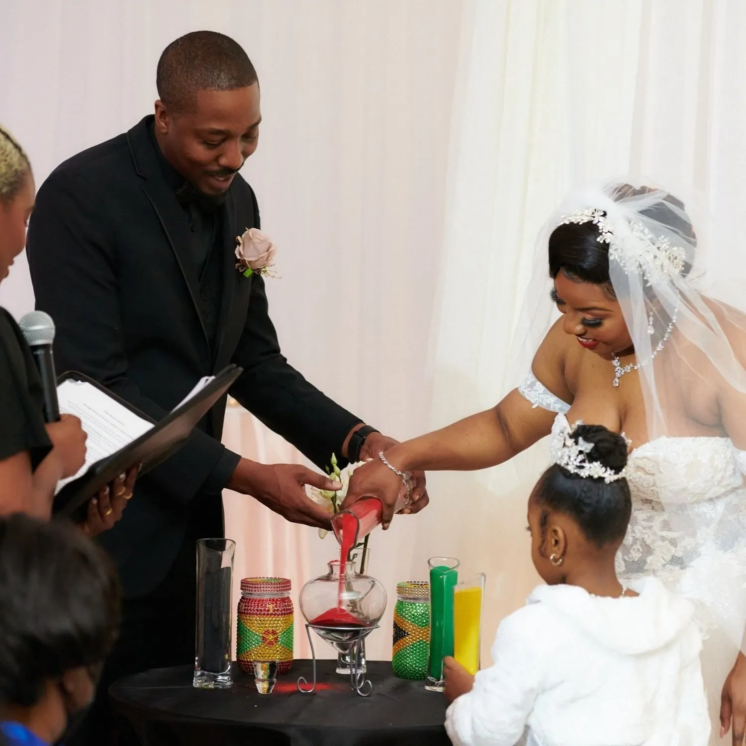 A couple pouring colored sand into a vase during their wedding