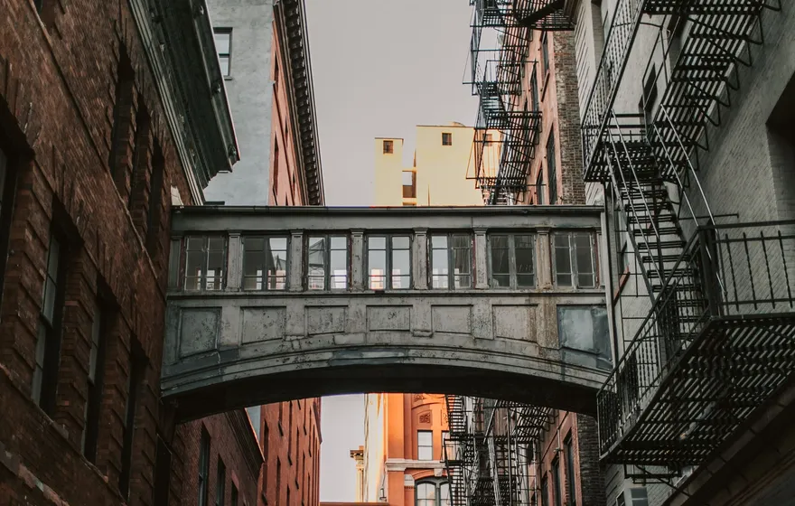 The Staple Street skybridge, an enclosed walkway between two red brick buildings, spanning a narrow cobbled Tribeca street