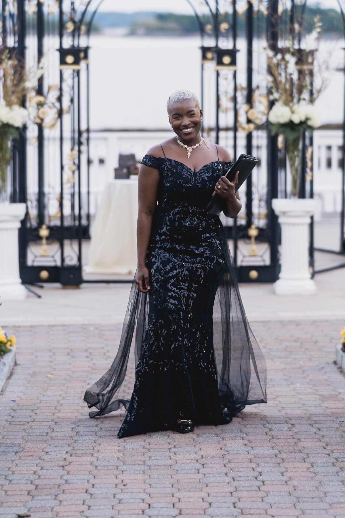 Robyn Walker arriving with her ceremony book at a waterside wedding altar