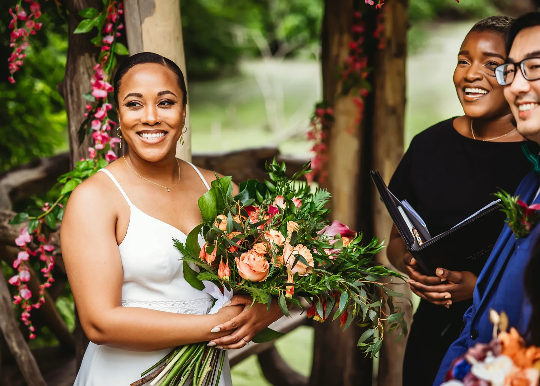 Robyn Walker with a newly married couple holding a bouquet after their ceremony