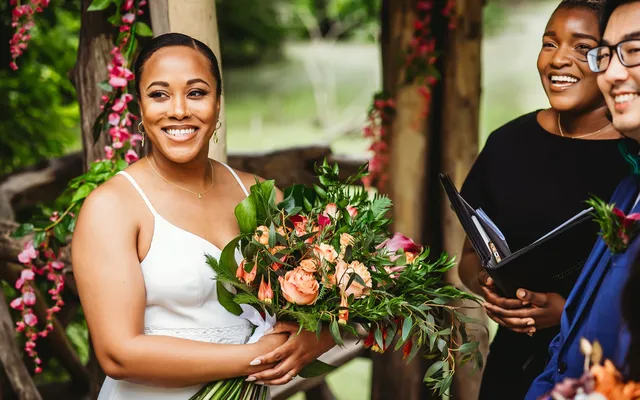 Robyn standing with a newly married couple holding a bouquet