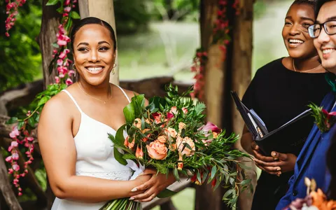 Robyn standing with a newly married couple holding a bouquet
