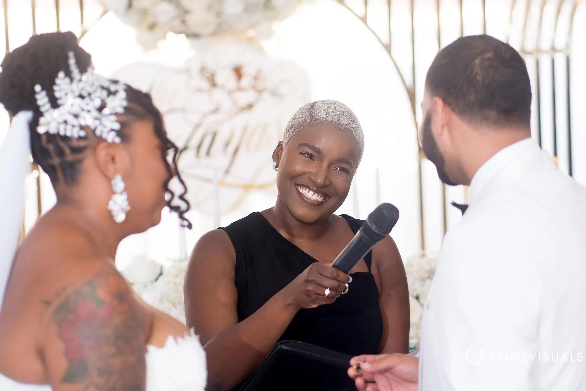 Robyn Walker smiling between a couple as she officiates their ceremony