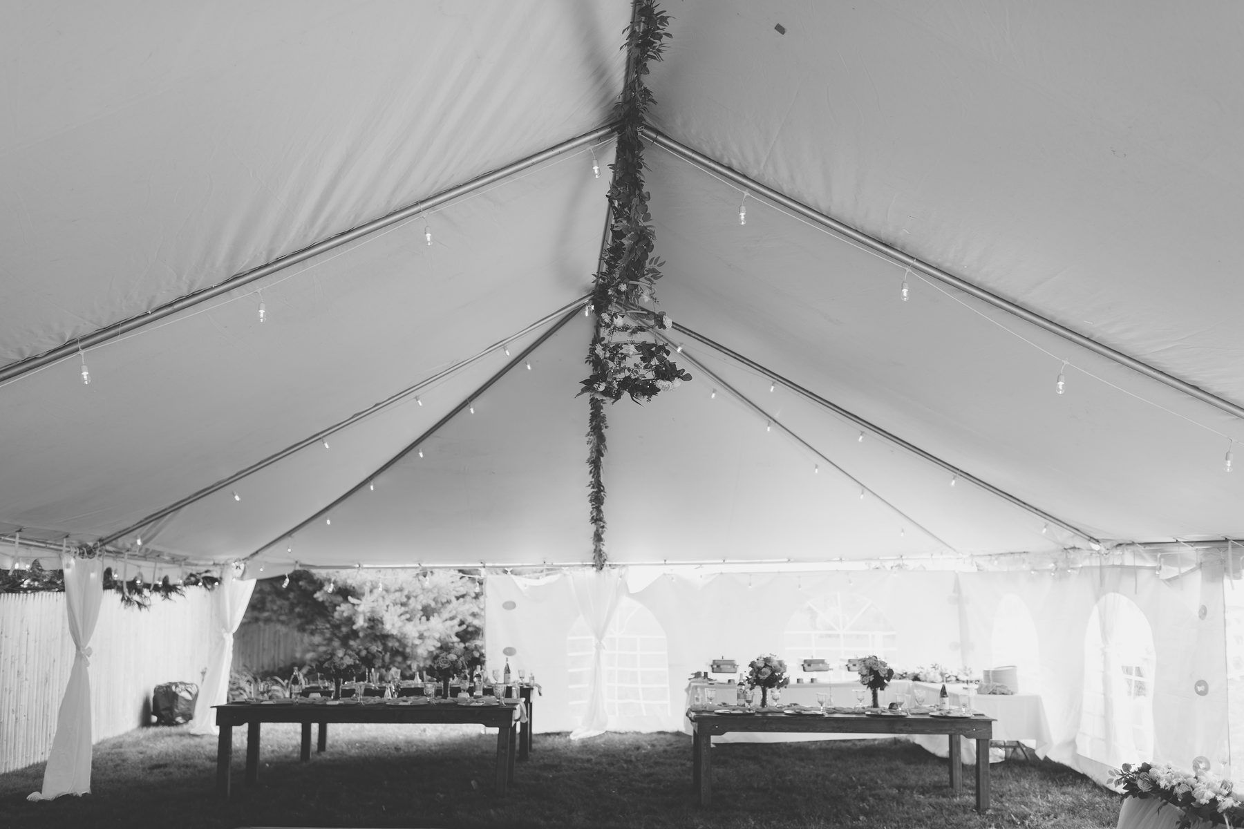 A tented backyard reception set and waiting before the ceremony, in black and white