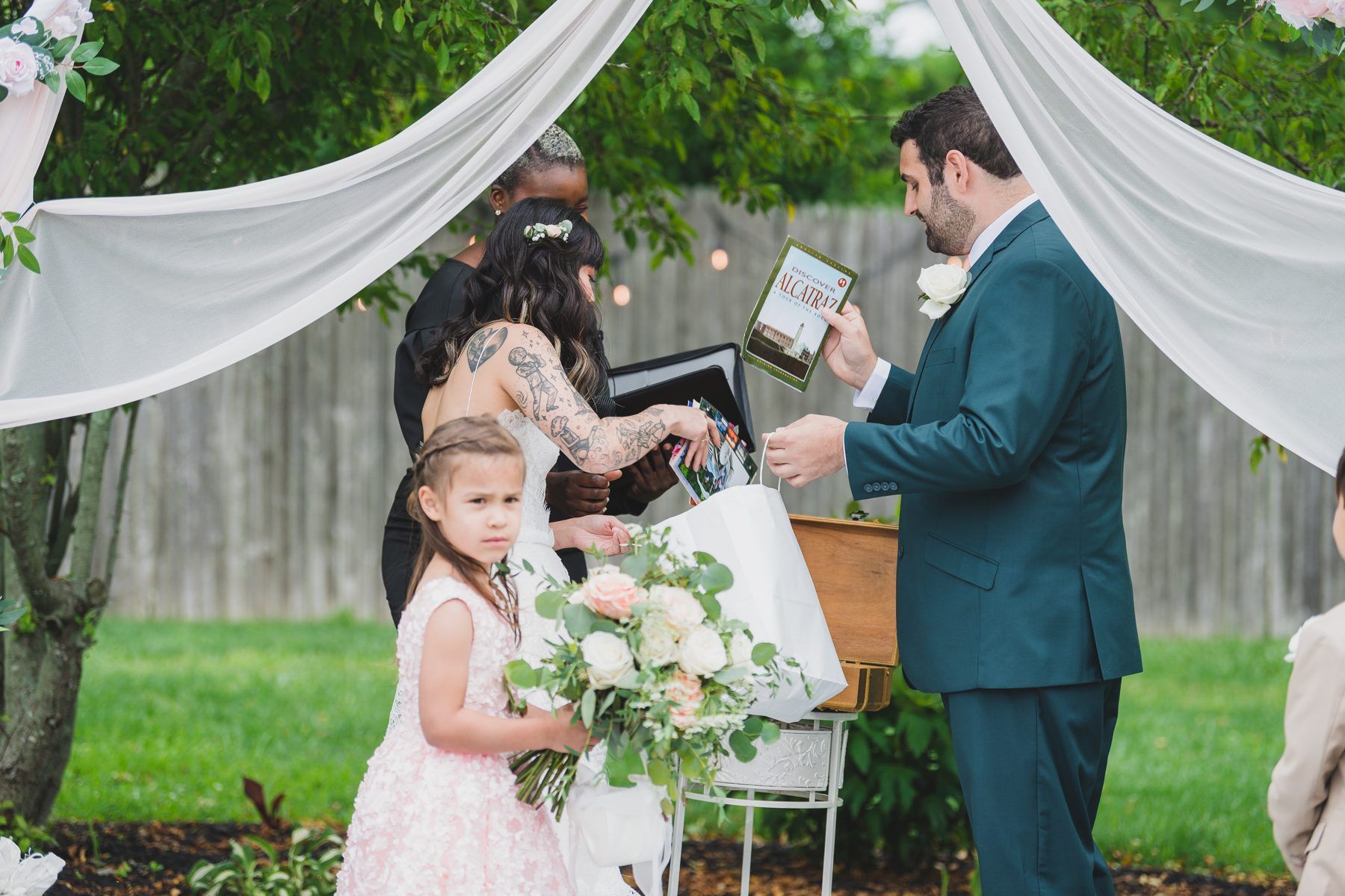A couple unpacking their unity ritual keepsakes under draped fabric at a backyard ceremony