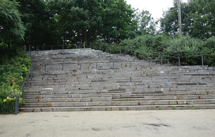 Wide granite steps rising like an amphitheater toward trees at Pier 1 in Brooklyn Bridge Park