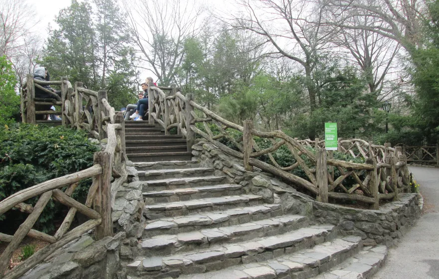 A curving flight of stone steps with rustic wooden railings climbing through Shakespeare Garden